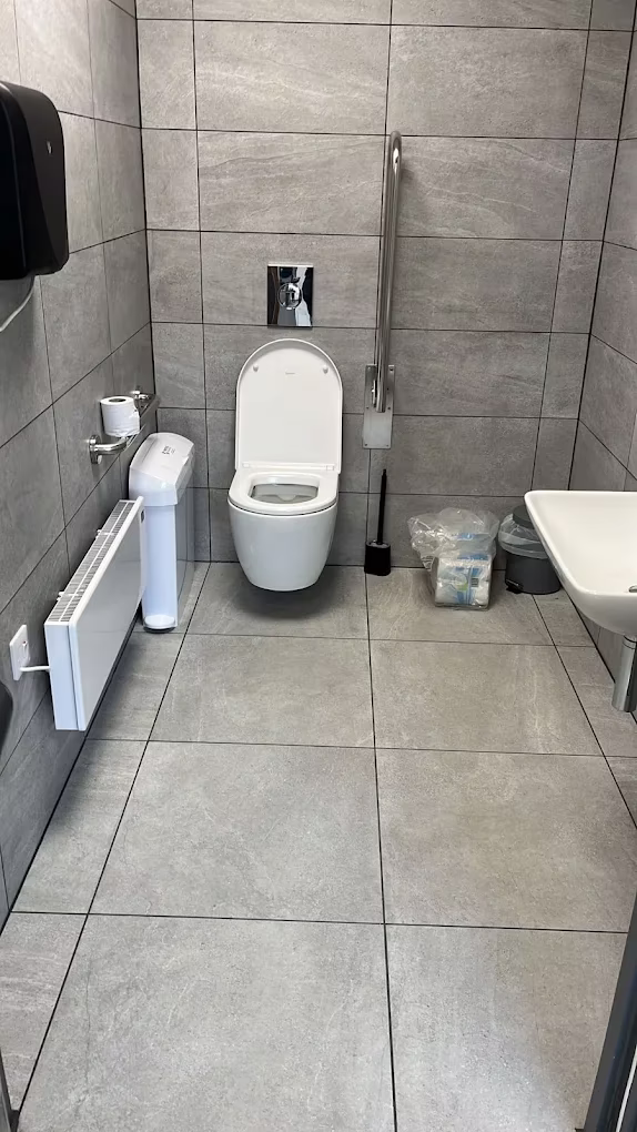 Finished bathroom with a wall-hung toilet, tiled floor and a slimline radiator