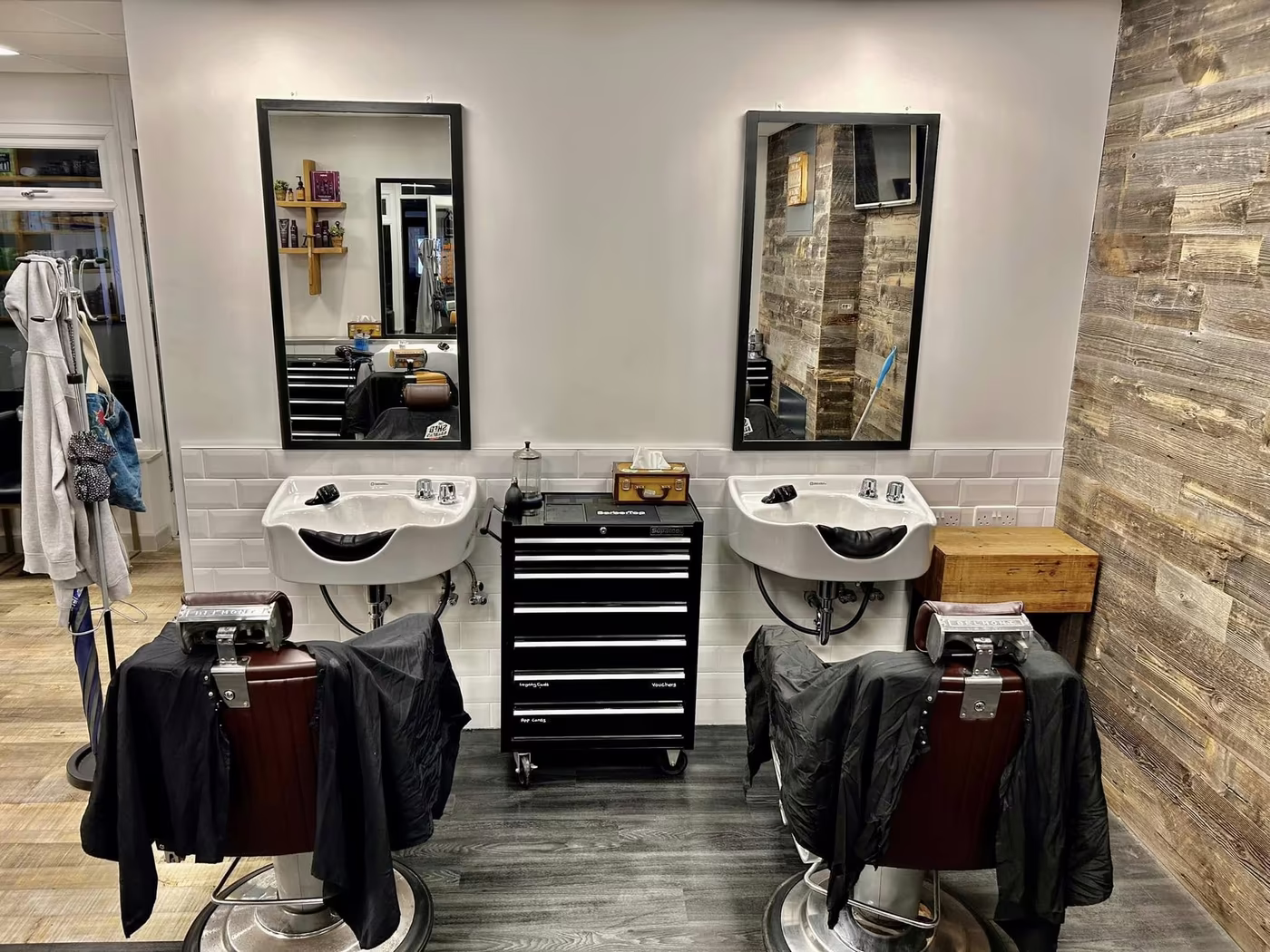 Finished barber shop interior with two chairs, basins and mirrors along a panelled wall