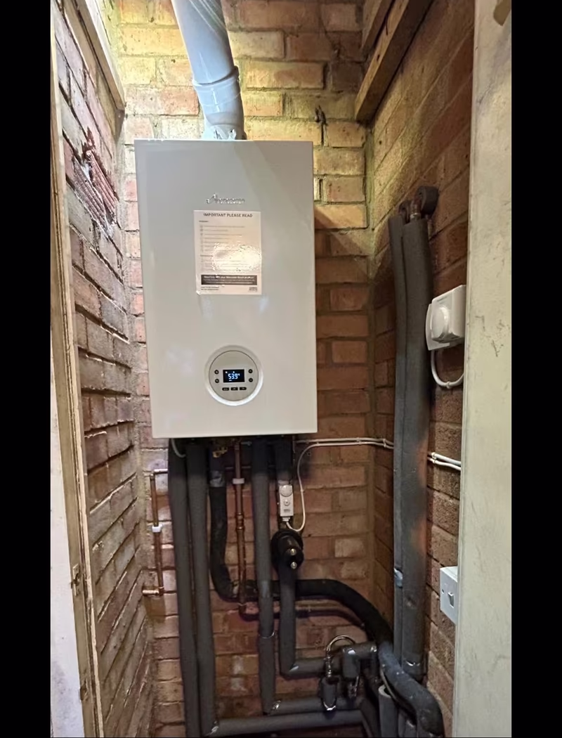 New Worcester boiler in the same brick alcove, install label still on it, pipework run straight